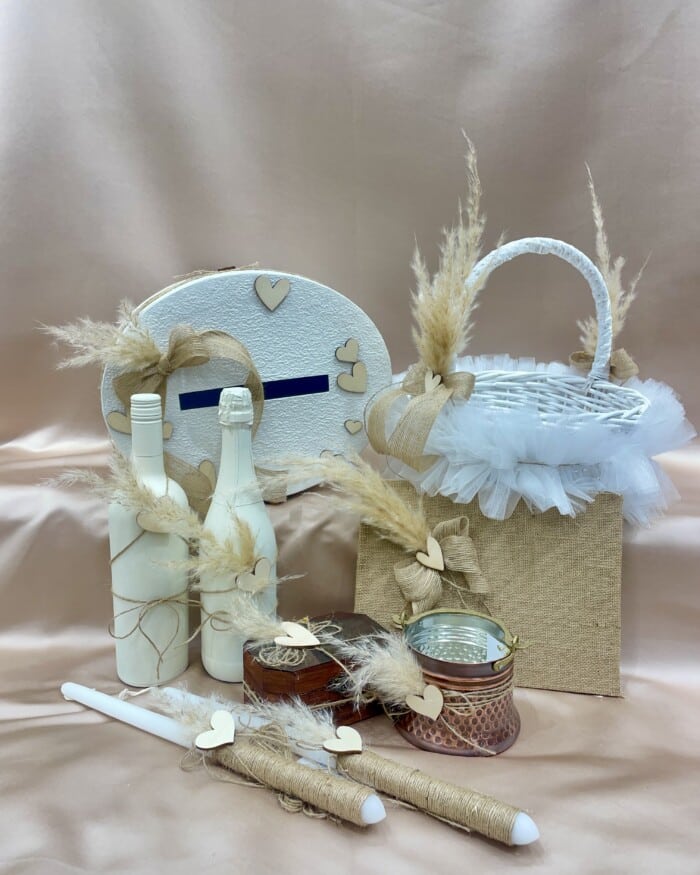 "Сватбен комплект с булчински аксесоари, включително кутия за пари и сватбен букет, подредени на фон на елегантен сатенен плат