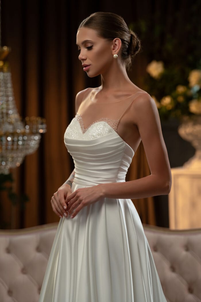 Елегантна булка облечена в класическа сватбена рокля Маделин с деликатни украшения от маниста и дълъг шлейф.