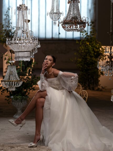 2024 Булчински дантелени рокли - модел Петра. Булка в елегантна сватбена рокля с дантела в лукзозна стая в кристални полилеи.