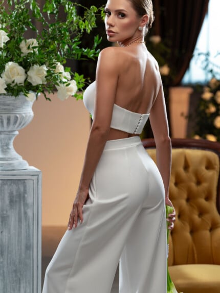 Модерен сватбен костюм с панталон, показан от елегантна билка в луксозен интериор.