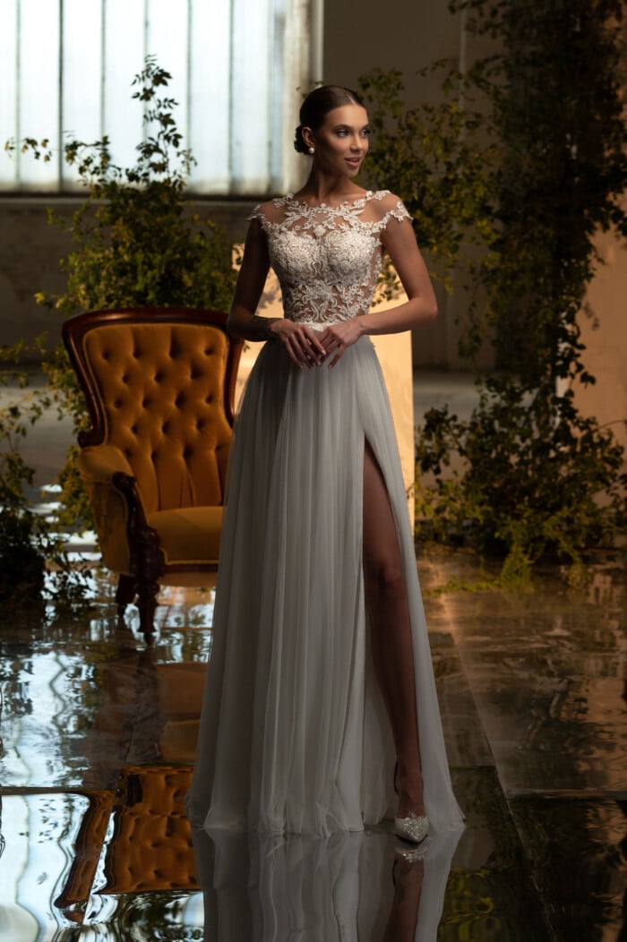 Елегантна сватбена рокля с прозрачен гръб и фини дантелени детайли, позиционирана в луксозен интериор.